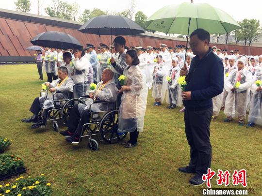 抗战老兵、纪念馆工作人员、现役官兵及小学生在烈士名单墙前整队肃立，哀悼先烈。　杨颜慈 摄